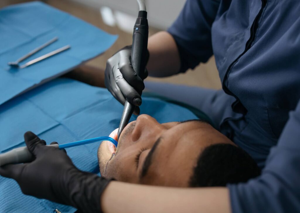 Dentist examining a patient's teeth for exposed tooth roots and gum recession during a routine dental evaluation.
